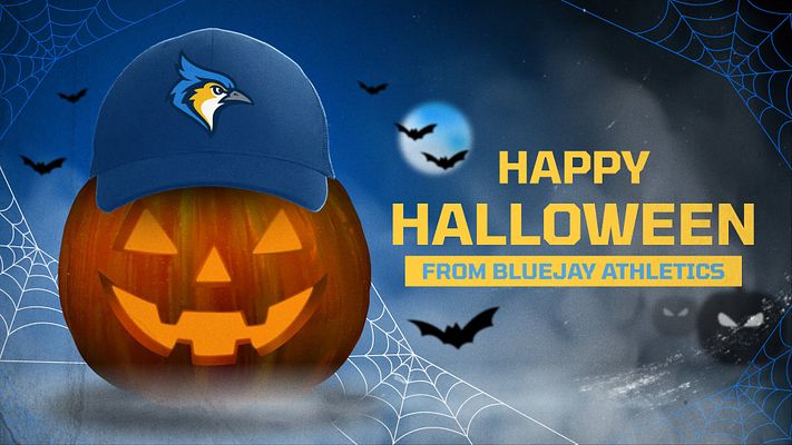 Halloween sports template featuring a jack-o'-lantern wearing a blue sports cap on left, with yellow "Happy Halloween" text and customizable team name area on right. Dark blue background with spider webs and flying bats creates festive mood.